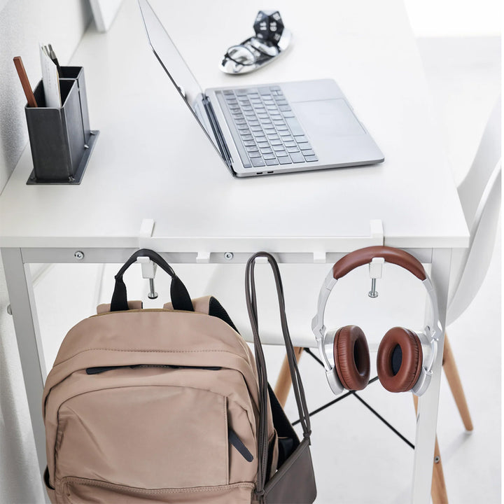 Gancho para mesa blanco de Yamazaki con mochila y audífonos